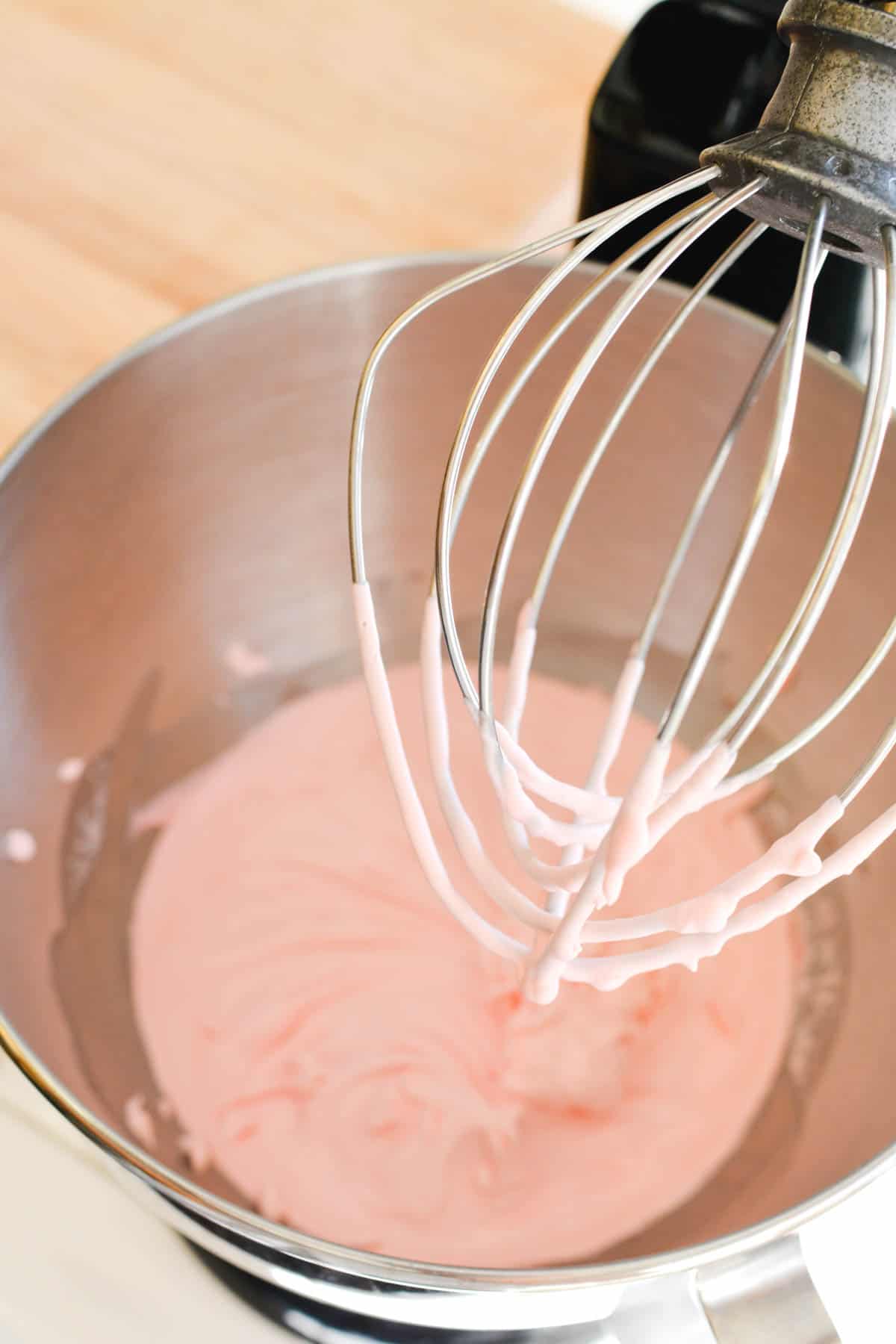 A stand mixer with pink whipped cream.