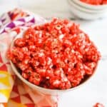 Close up of a white bowl holding Jello Popcorn with a cherry flavored candy coating.