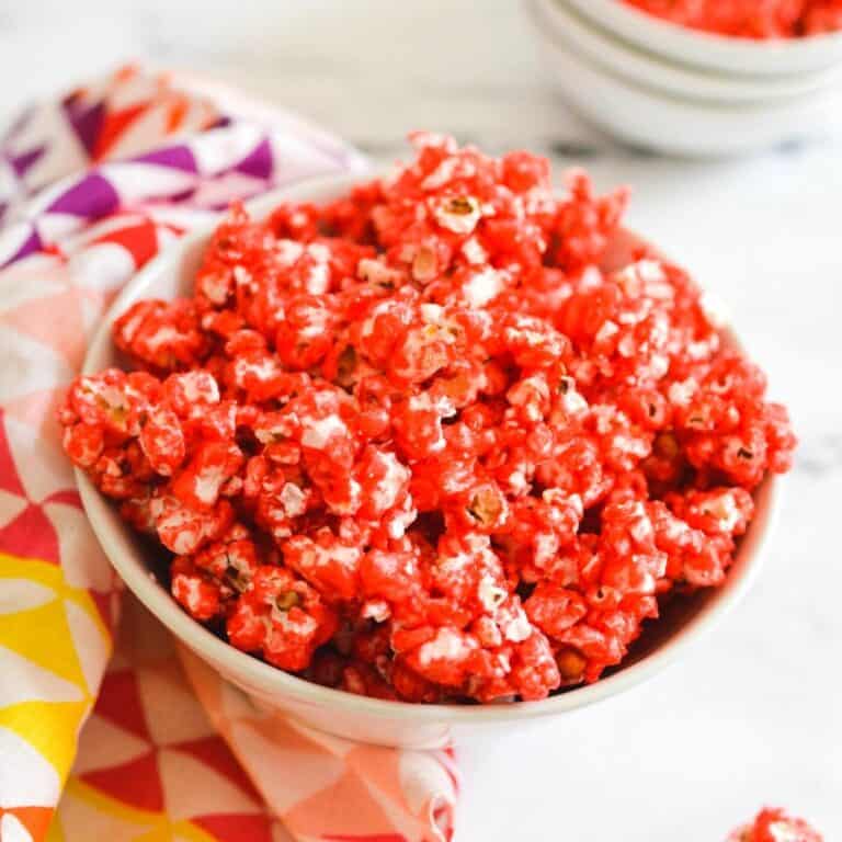 Close up of a white bowl holding Jello Popcorn with a cherry flavored candy coating.