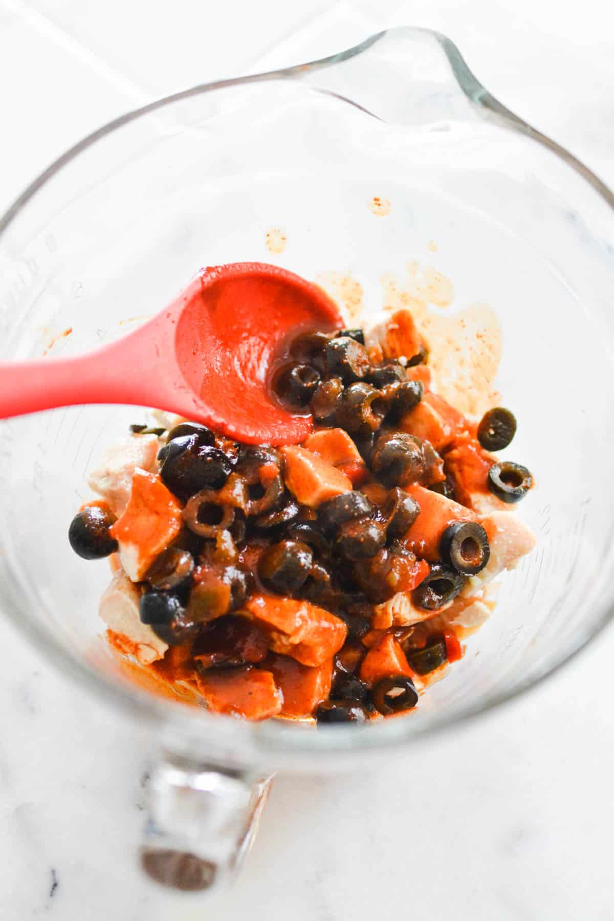Mixing bowl with chicken, manwich enchilada sauce and black olives.