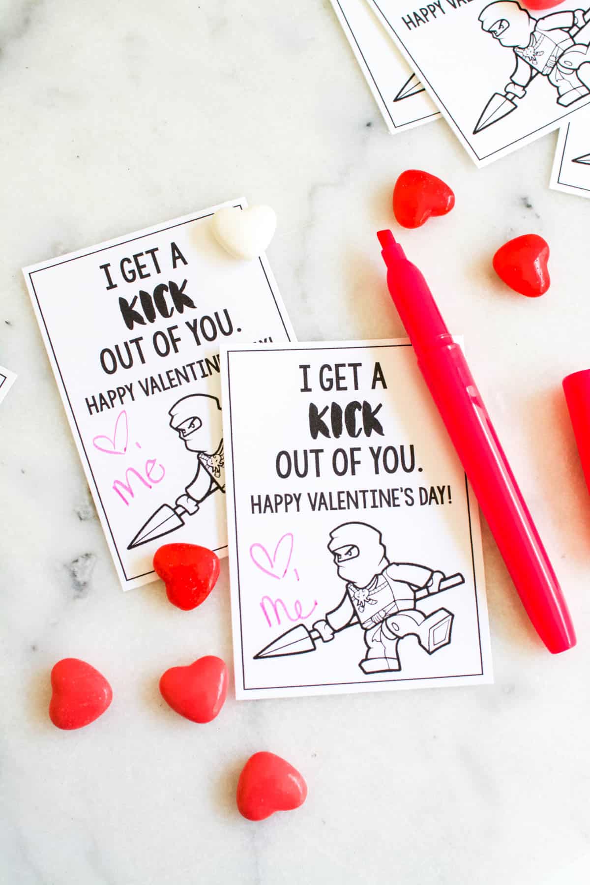 Ninjago Valentine's cards on a table next to heart shaped candies.