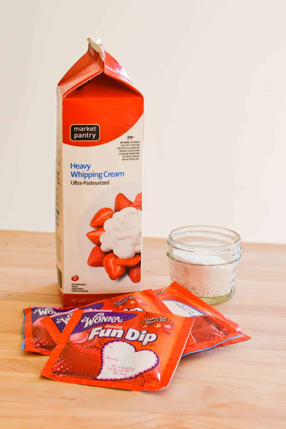 Ingredients for flavored whipped cream with cherry fun dip candy.