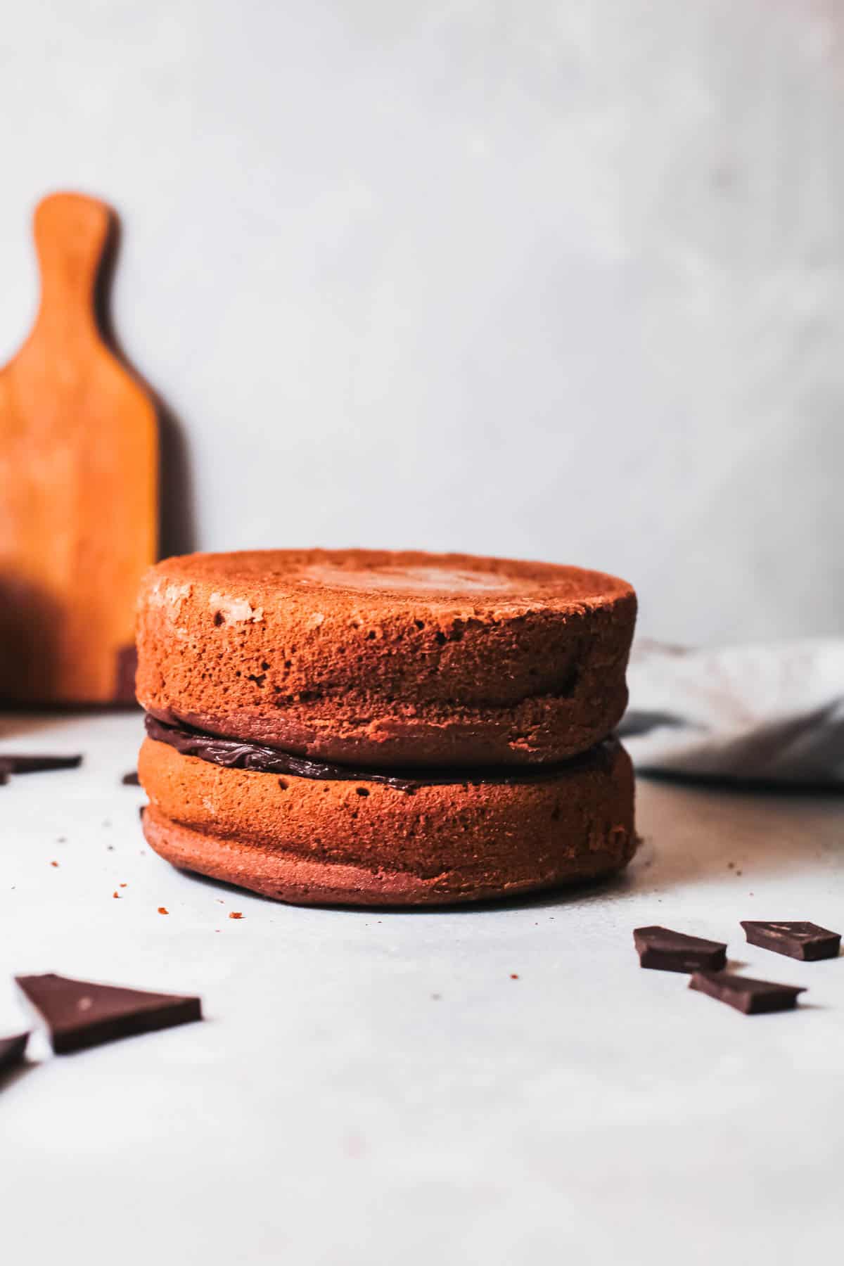 Two layers of chocolate cake stacked on top of each other with truffle ganache filling in the middle on a counter. 