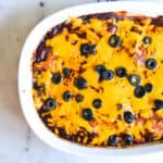 Close up of a portion of a casserole dish holding a chicken enchilada casserole.