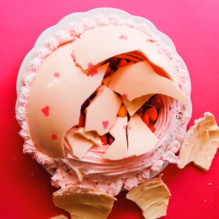 candy surprise cake topped with a white chocolate dome.