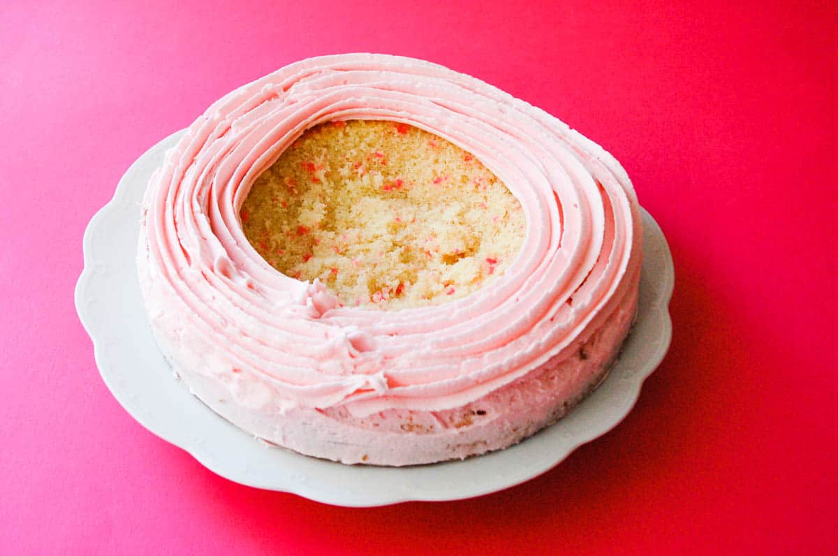 A cake topped with a ring of pink frosting.