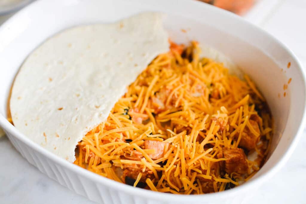Baking dish with layers of chicken, cheese and tortilla.