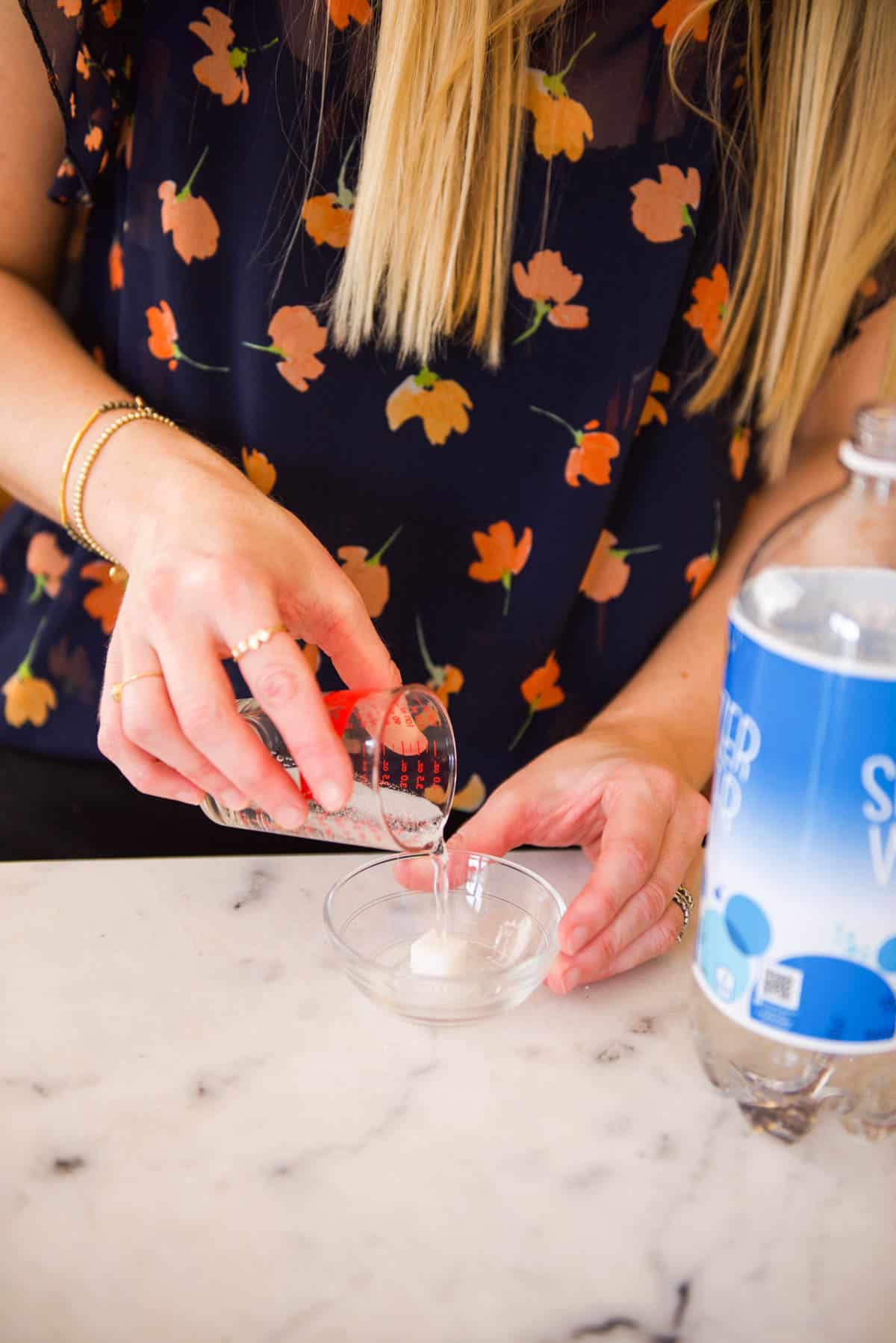 Adding club soda to a small bowl with a sugar cube.