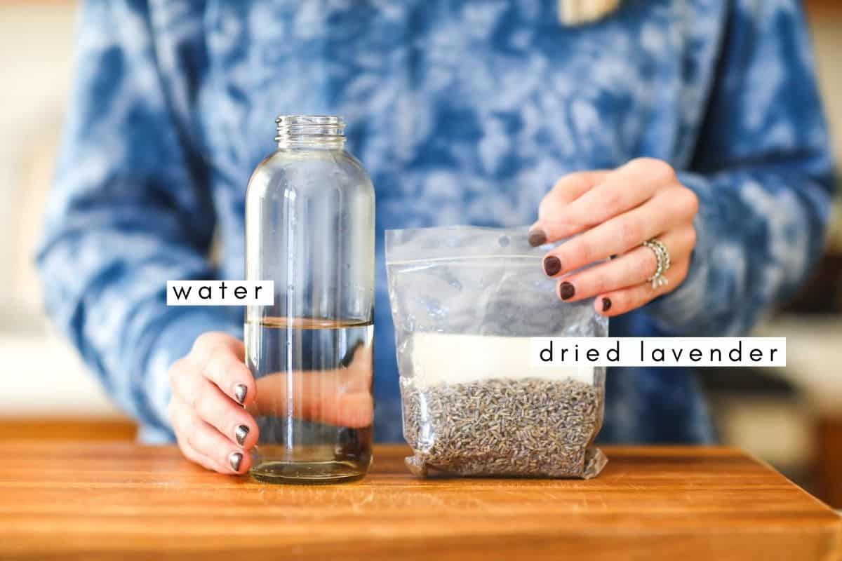 Woman holding a bottle of water and a bag of dried lavender flowers.