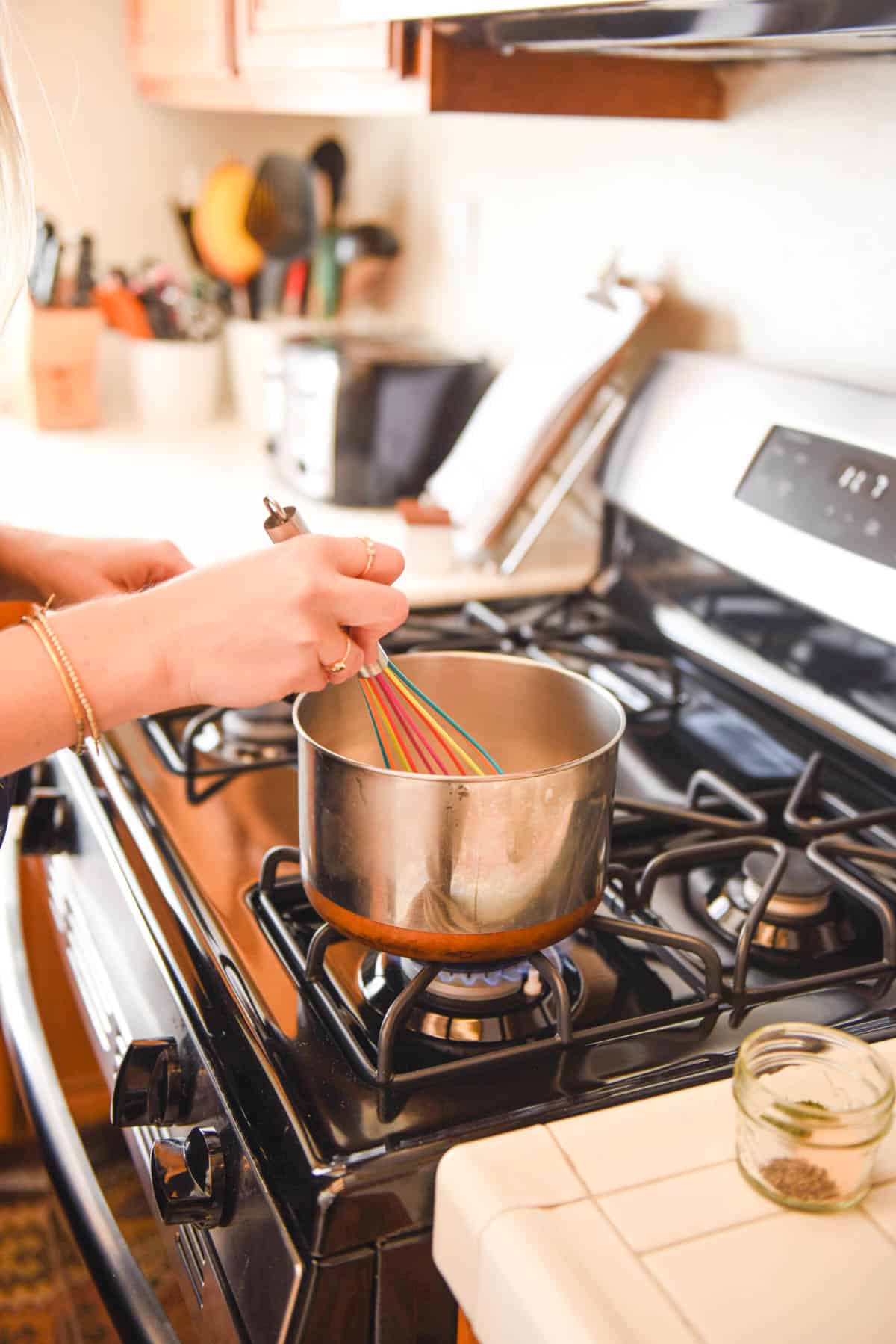 Woman mixing something in a saucepan on the stove.
