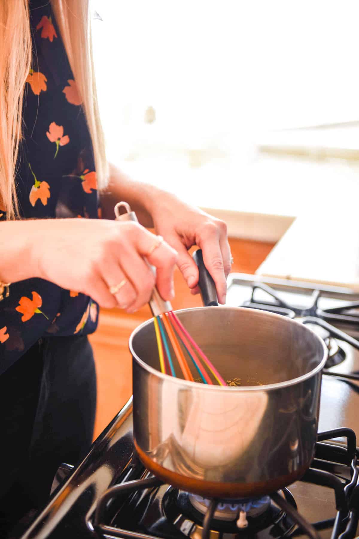 Woman mixing beer cheese in a pan on the stove.