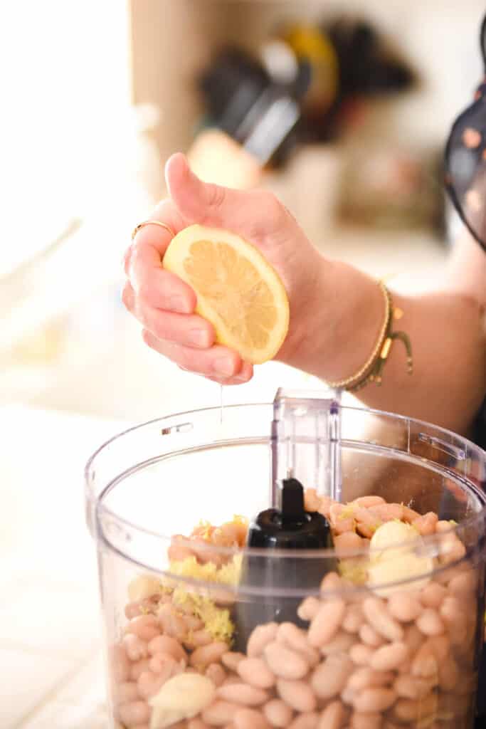 Woman squeezing lemon into a food processor.