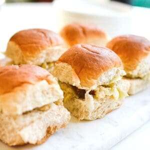 Close up view of sweet hawaiian roll sliders with artichoke dip.