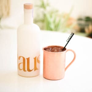 Close up of a bottle of Lemon Lavender Haus next to a copper Mule mug with stir stick.