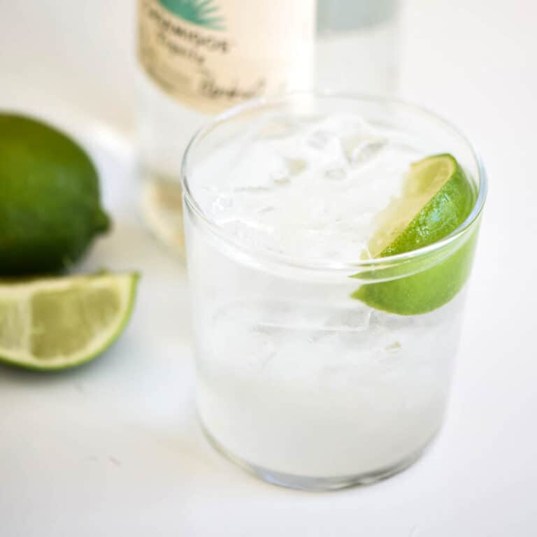 Close up of a cocktail on a counter with a lime garnish.