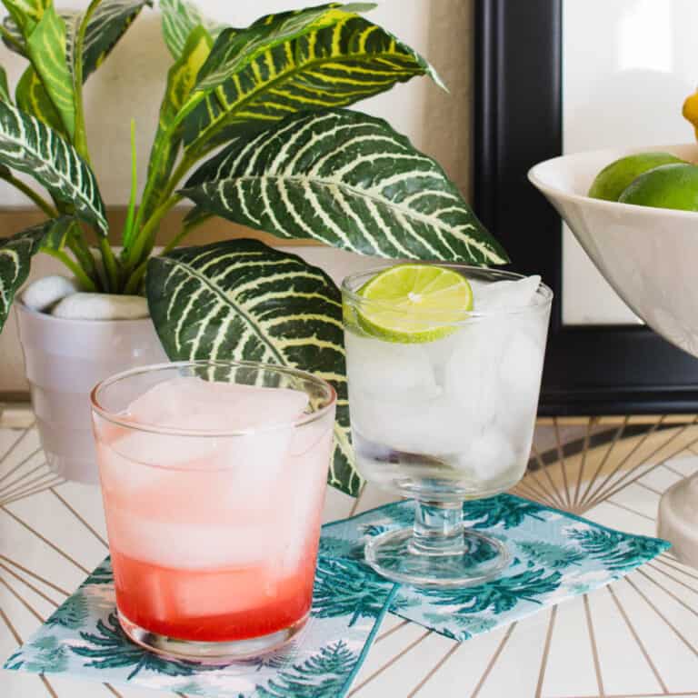 Two ingredient drinks on napkins on white table.