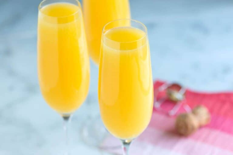 Close up of 3 mimosa cocktails in champagne flutes.