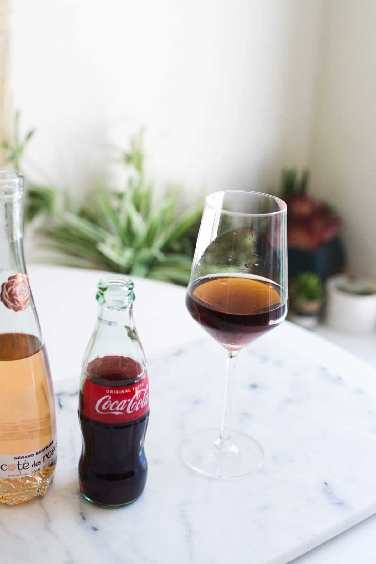 A wine glass with coke and rosé on a table.