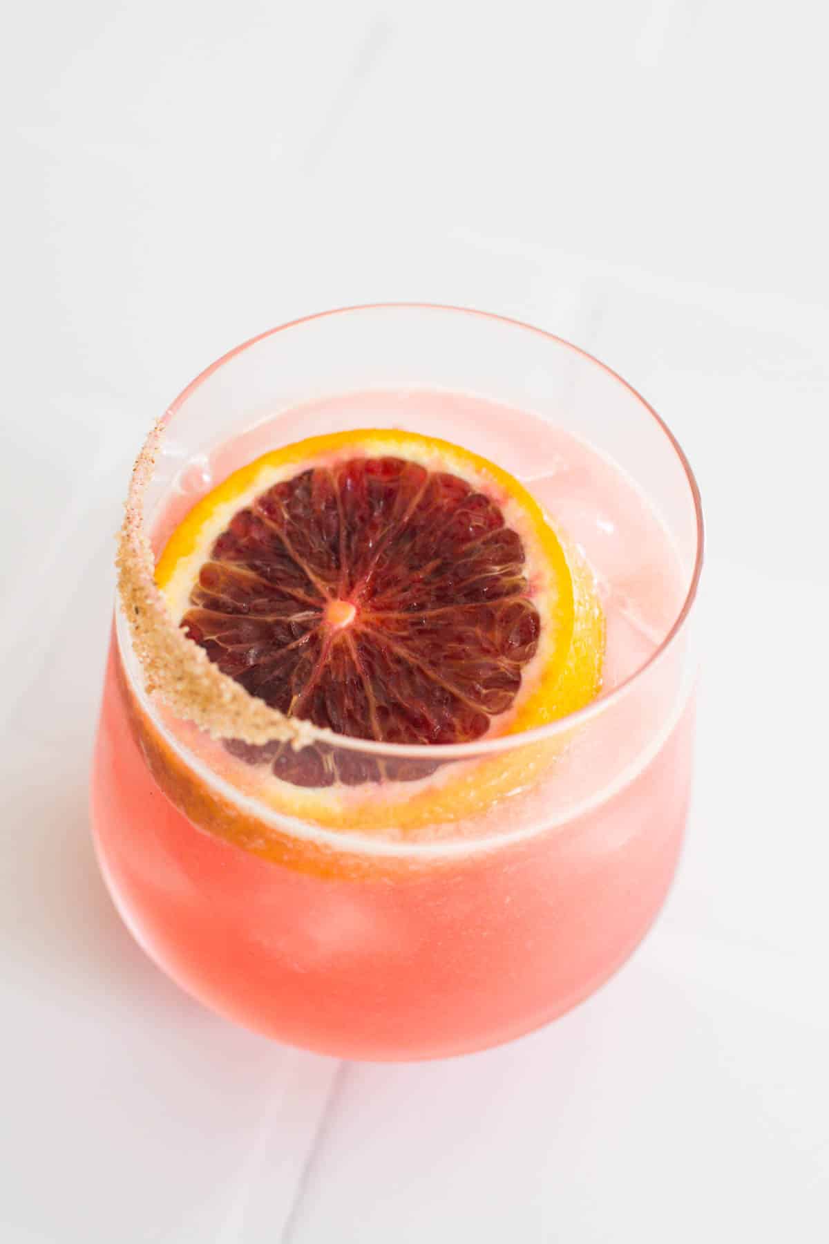 A cocktail glass with a blood orange tequila cocktail with a fresh slice of blood orange.