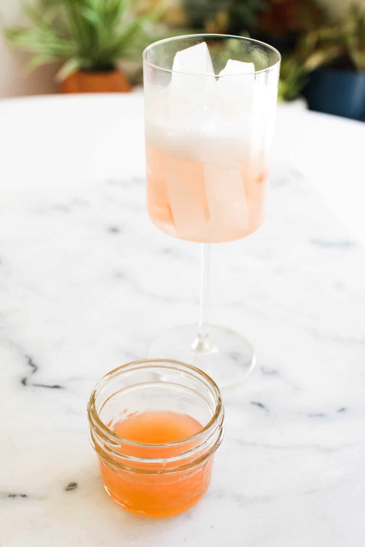 A small bowl of fresh grapefruit juice on a table in front of a wine glass.