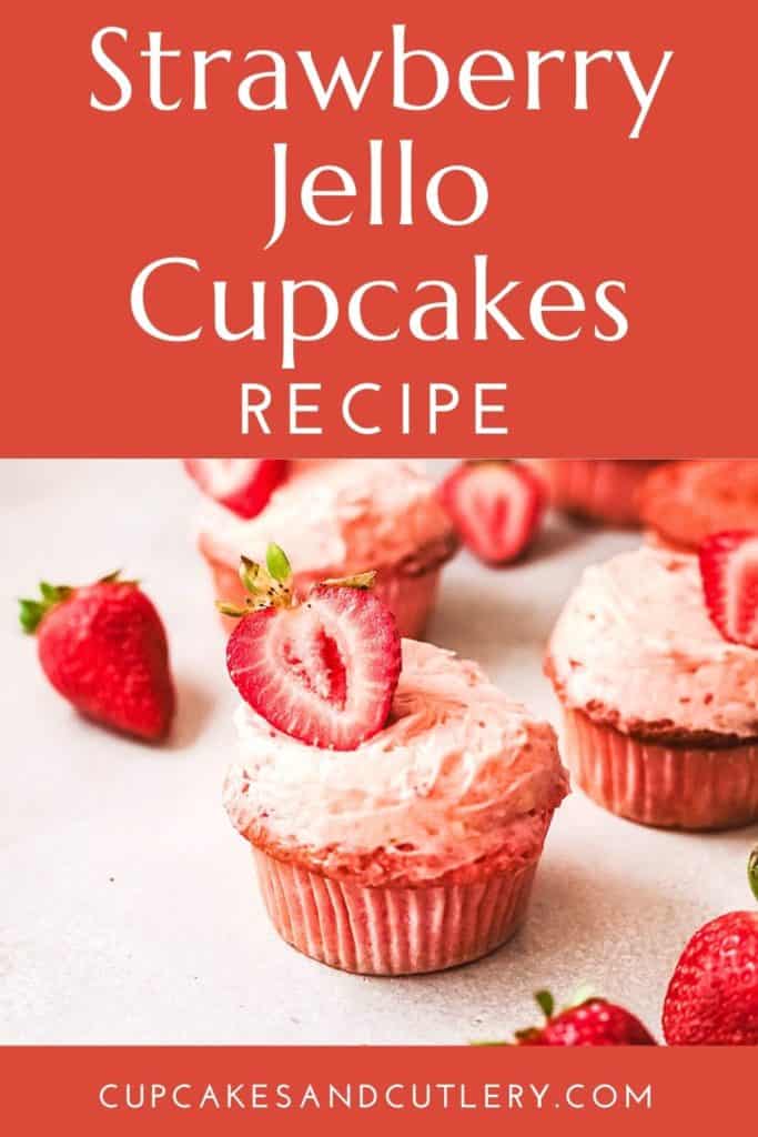 A pink Strawberry Jello Cupcake topped with pink frosting and a fresh strawberry.