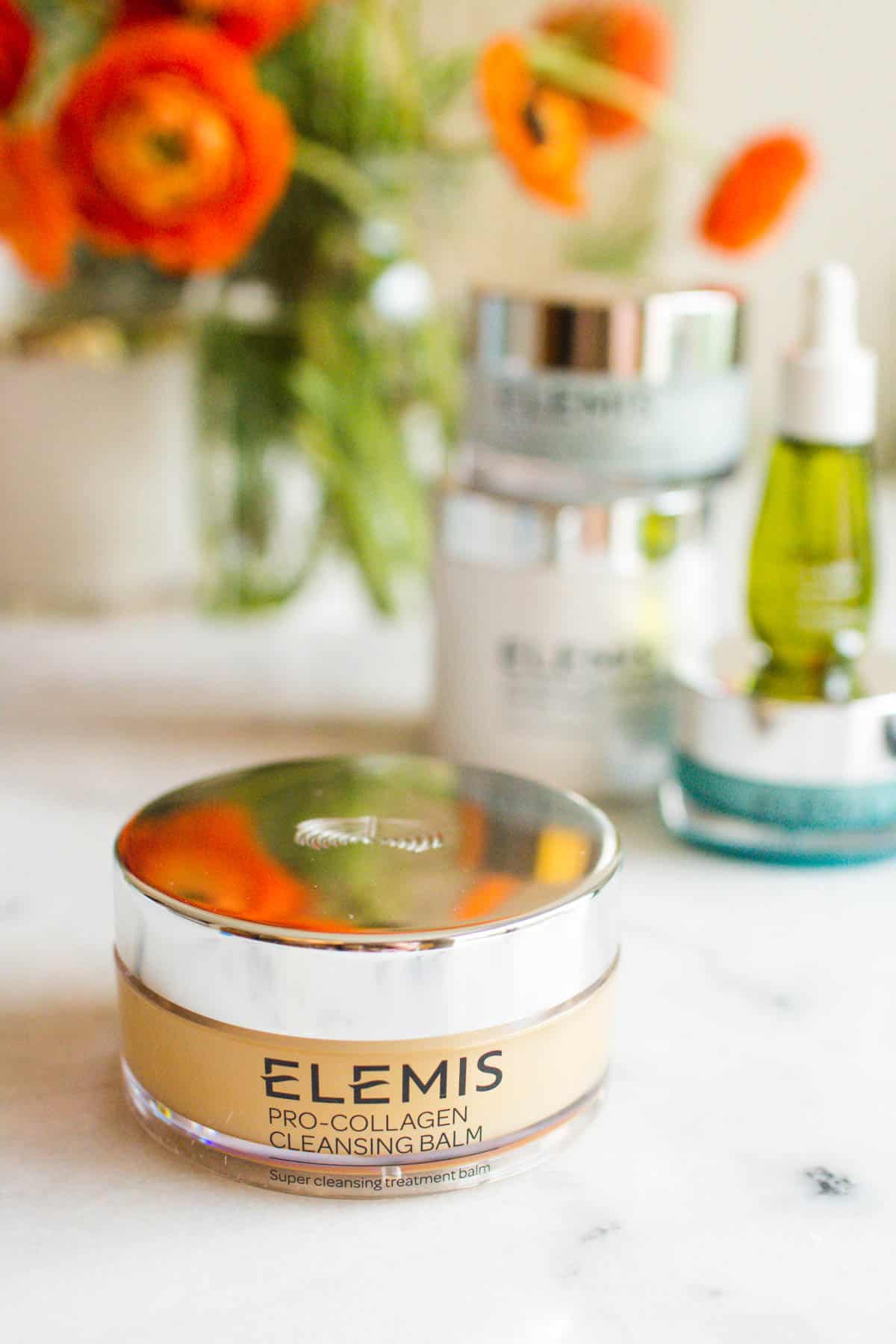 Elemis Pro-Collagen Cleansing Balm on a counter with other Elemis skincare products in the background.