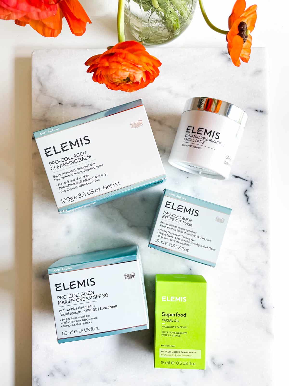 Overhead view of Elemis Skincare products in their boxes on a marble table.