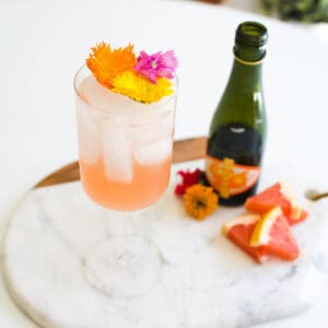 Close up of a wine spritzer topped with flowers on a tray.