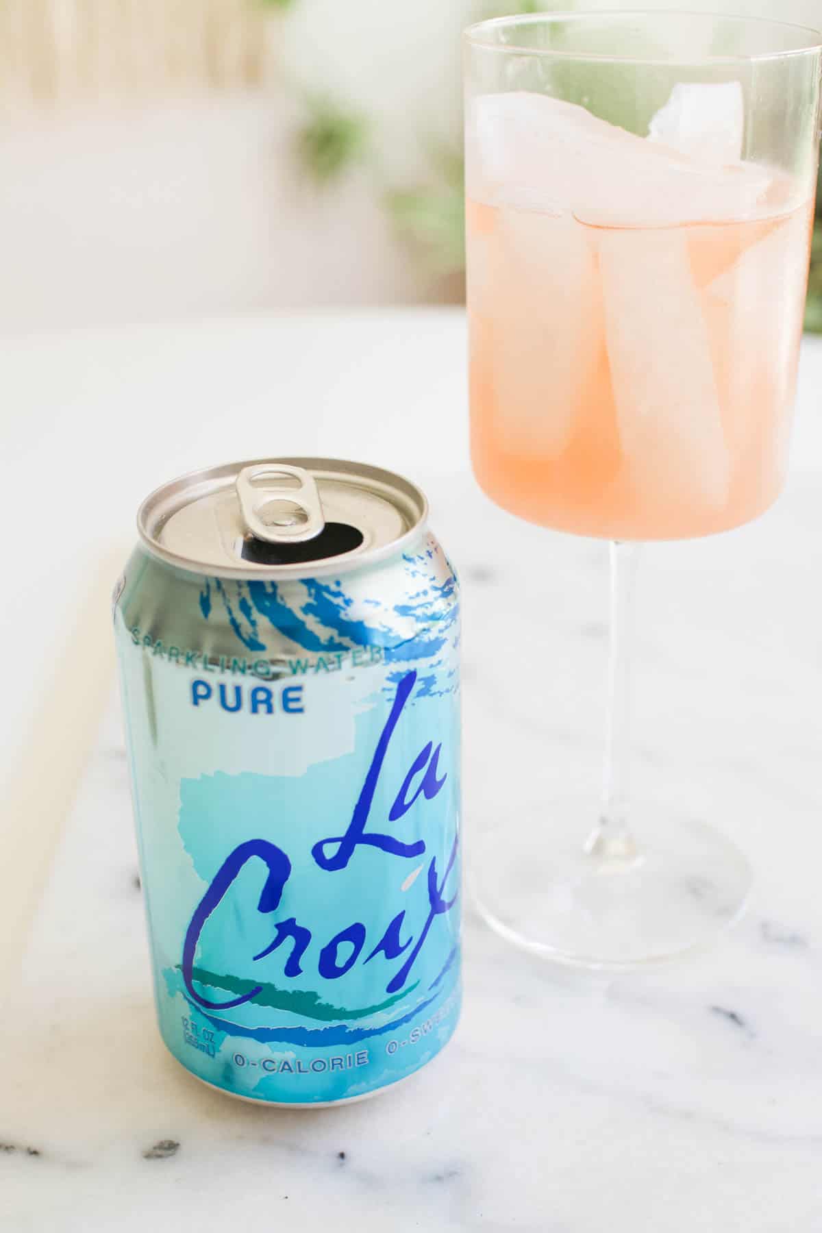 A can of club soda on a table with a spritzer on a table.