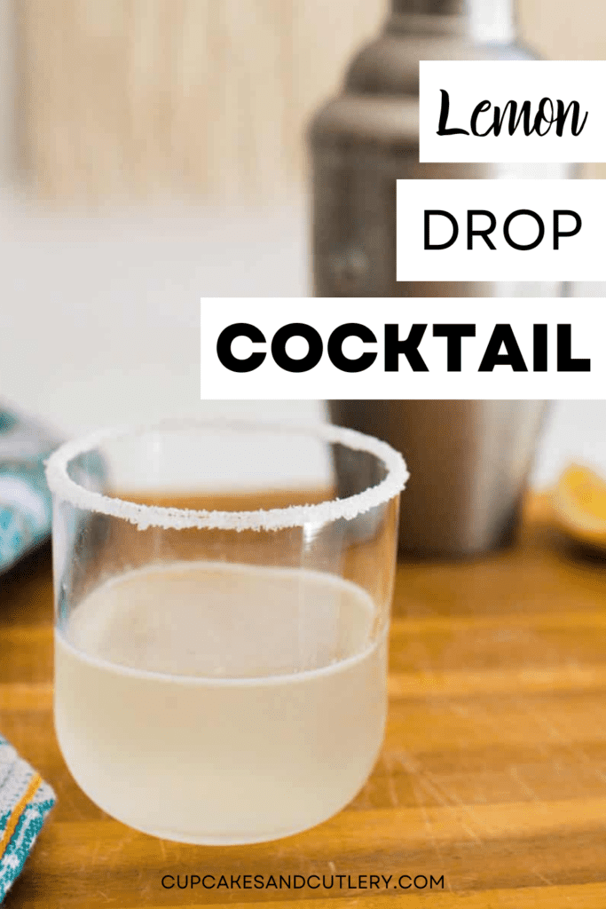 Short cocktail glass with Lemon Drop cocktail with vodka with a cocktail shaker in the background.
