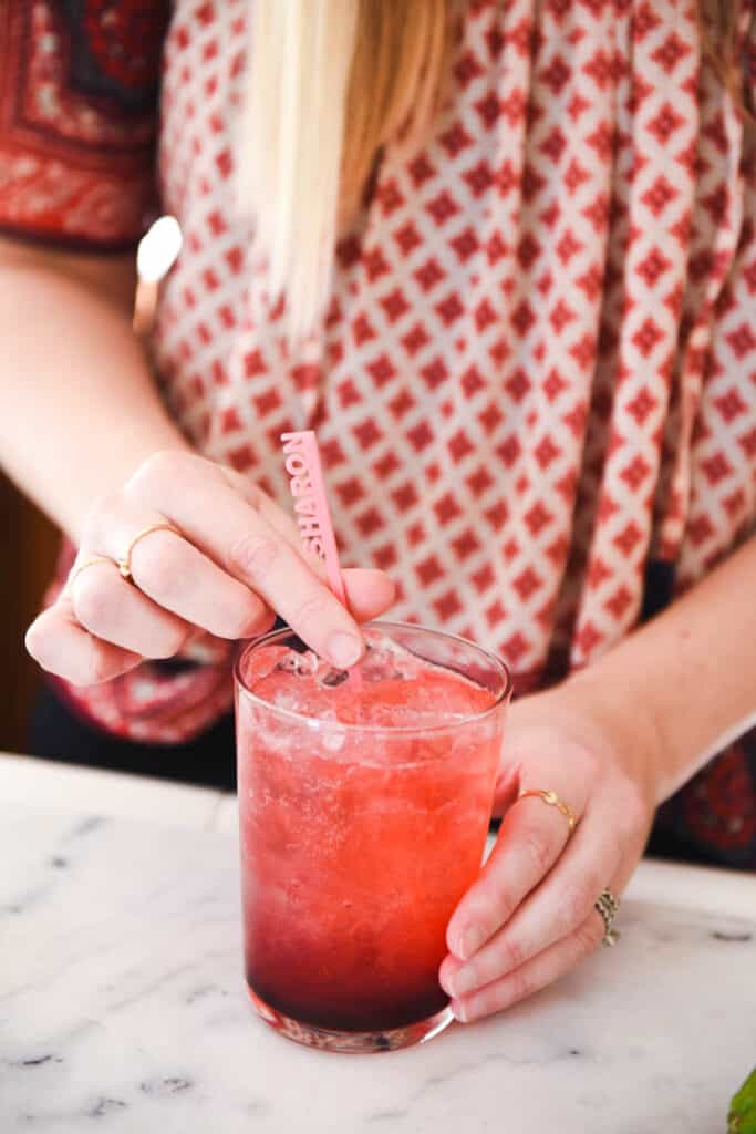 Woman adding a cocktail stirrer to a cocktail.