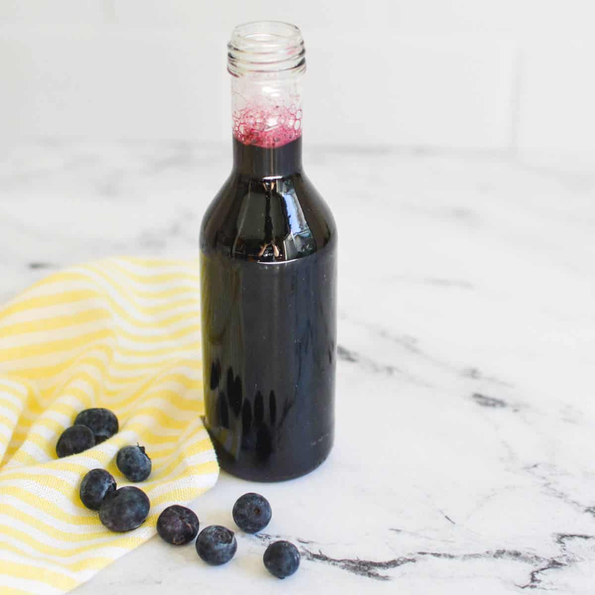 A close up of a bottle full of simple blueberry simple syrup.