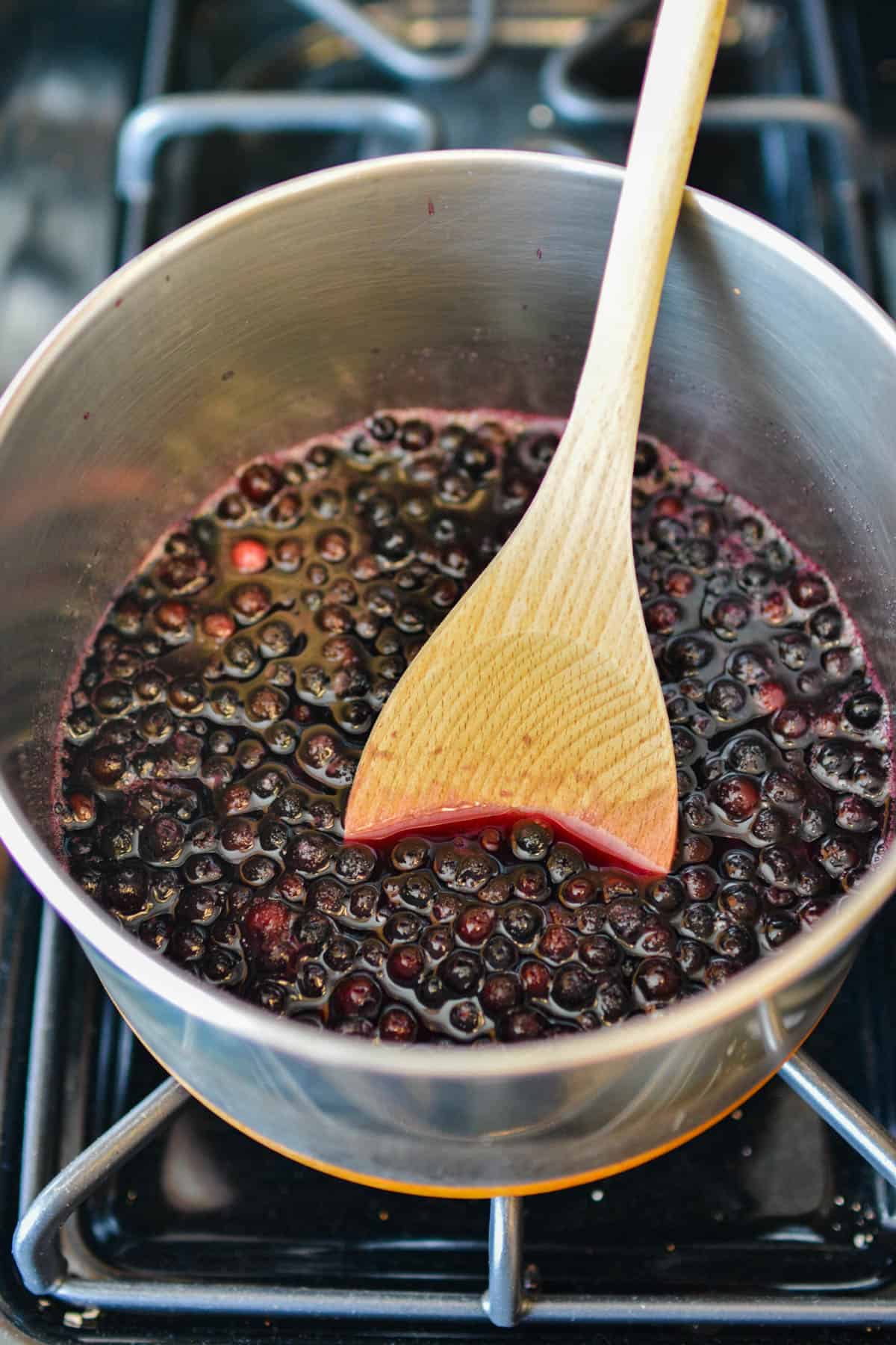 A saucepan full of blueberries cooking on the stove to make blueberry simple syrup.