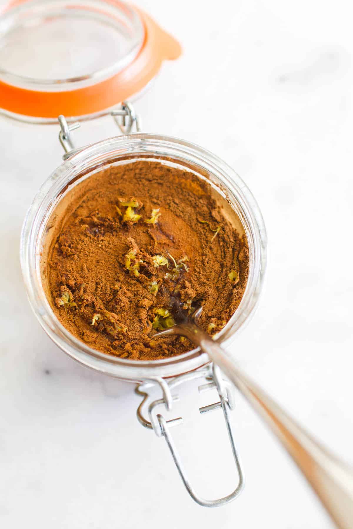 An open glass jar with honey and spices and a fork stuck in to mix it.