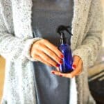 Woman holding a bottle of room spray made from essential oils.