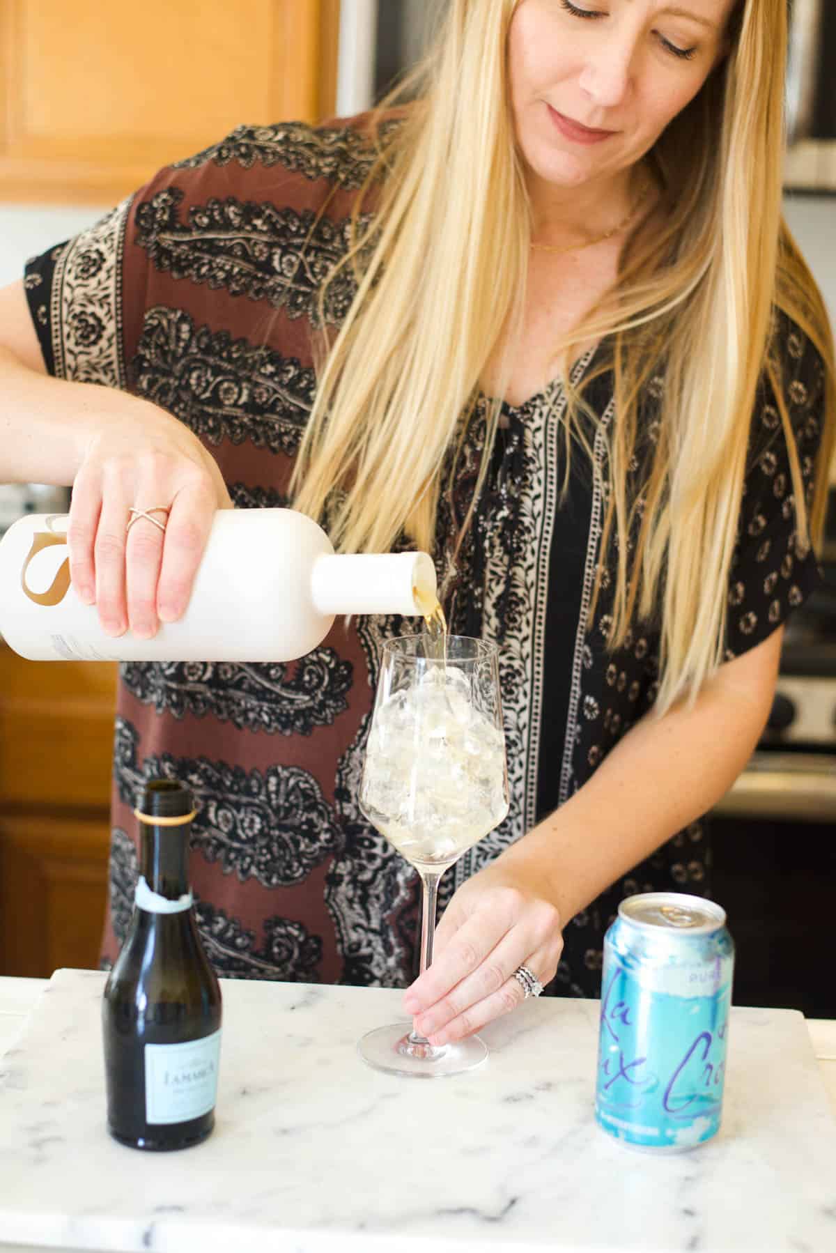 Woman adding Haus aperitif to a wine glass.