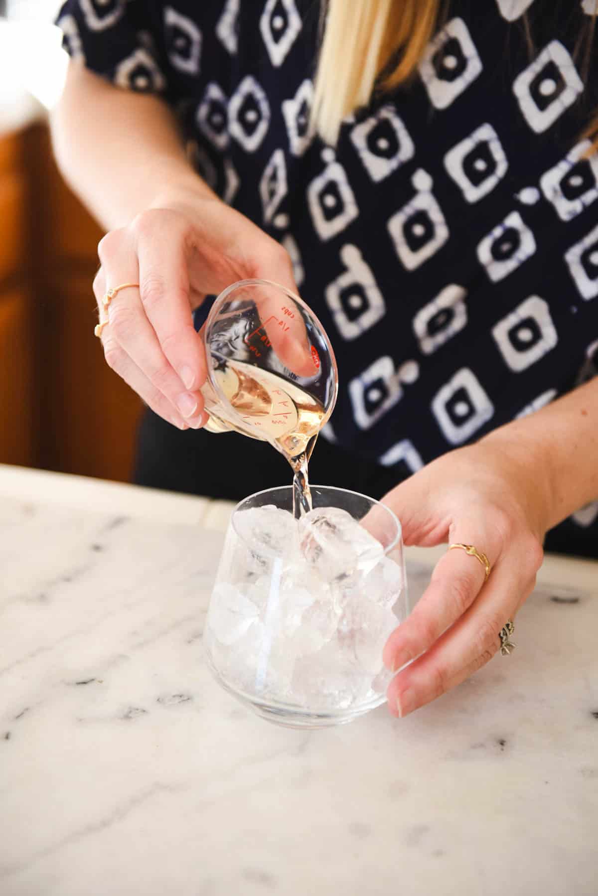 A women pouring in a shot of tequila to the ice in the glass of this tequila and coke recipe.