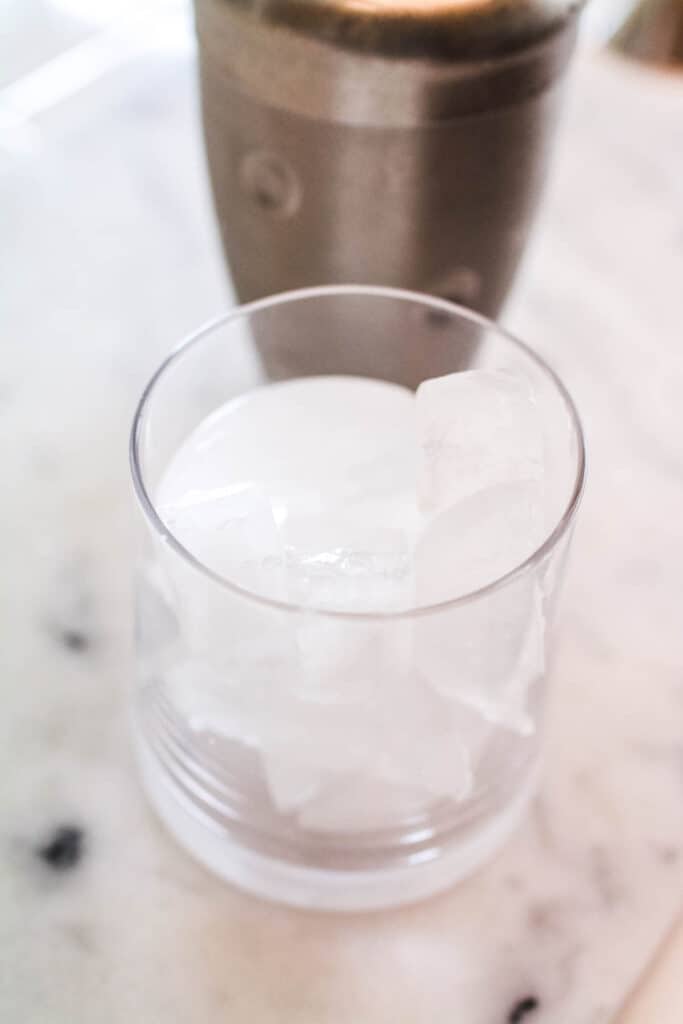 A cocktail glass on a counter with ice.