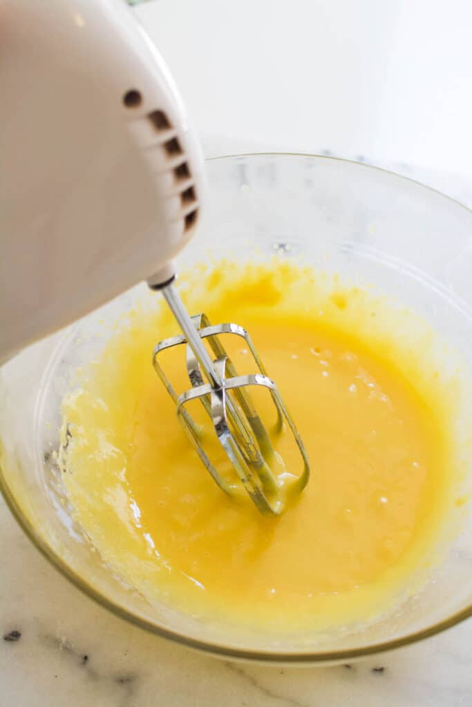 A hand mixer in a bowl of mixed pudding and milk.