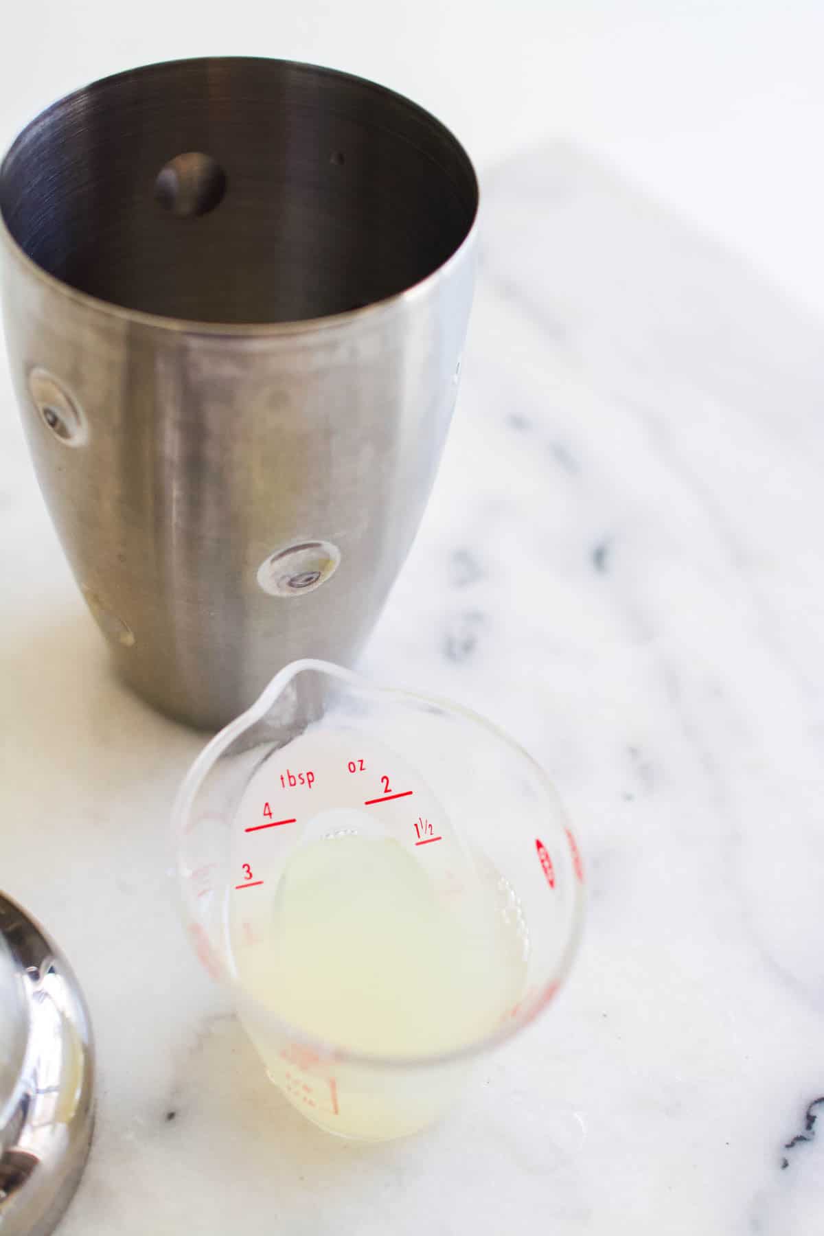 Adding ingredients for a margarita into a cocktail shaker.