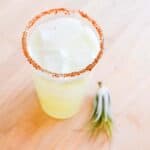 A Cucumber Margarita with Tajin rim on a table.