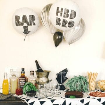 A party table with balloons that say bar with an arrow pointing down and "HBD bro".