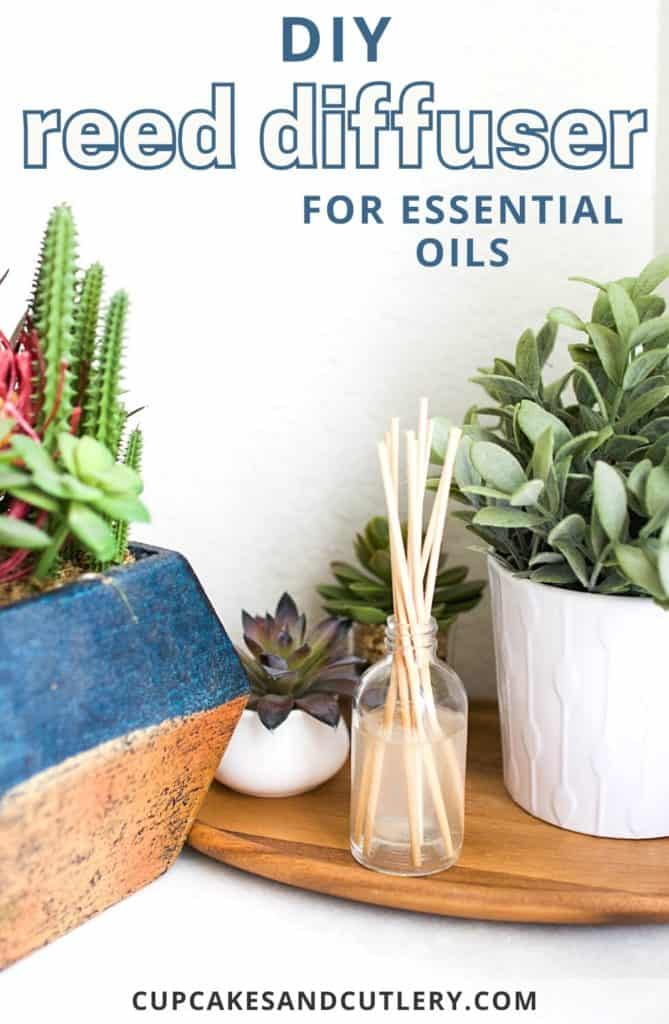 Image contains a DIY reed diffuser for essential oils on a wood tray surrounded by plants.