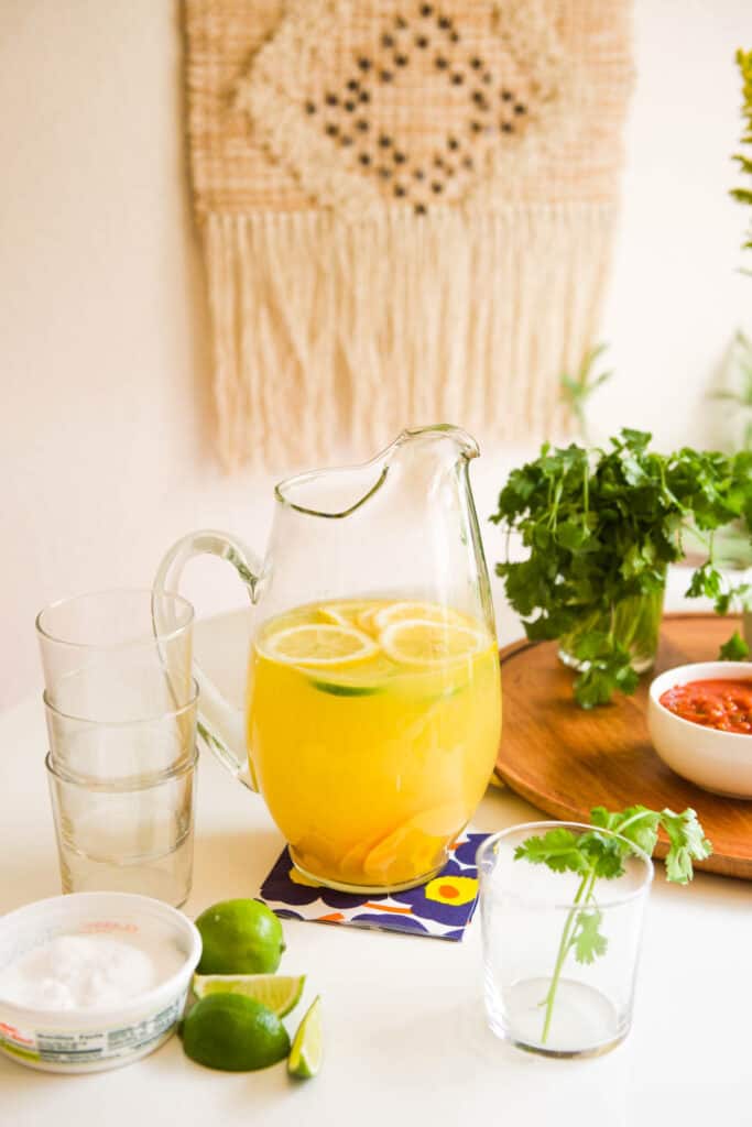 A pitcher full of Margarita Sangria recipe with empty glasses on the table.