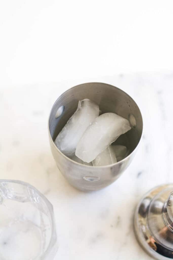 Adding ice to a cocktail shaker. 