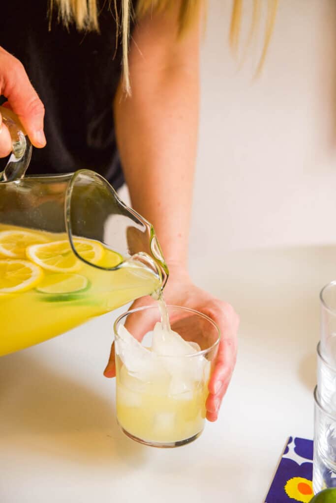 Pouring a pitcher or margarita over ice in a cup.