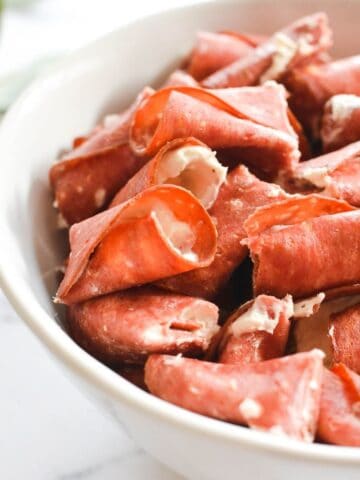 Close up of a white serving bowl with cut up Dried Beef Roll Ups.