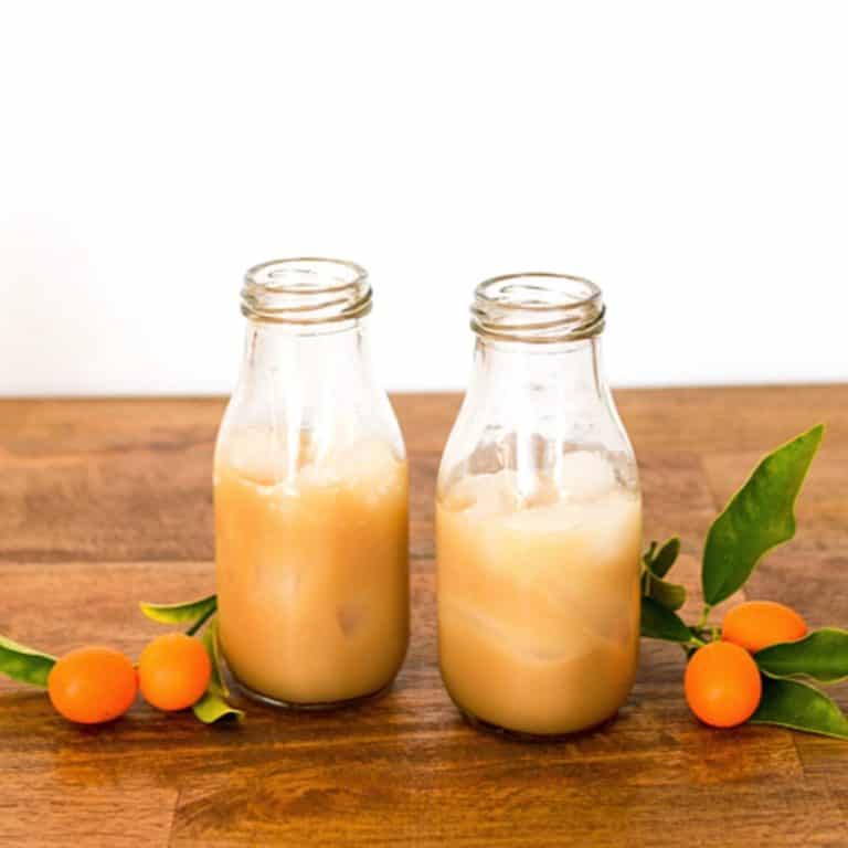2 small glass bottles with a Kahlua and Coconut Rum White Russian Cocktail on a table.