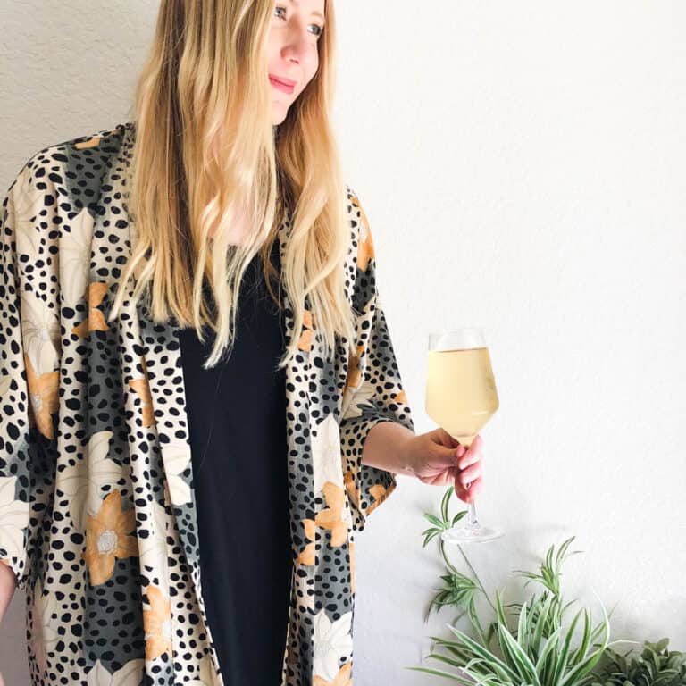 Woman holding a wine glass with white wine.
