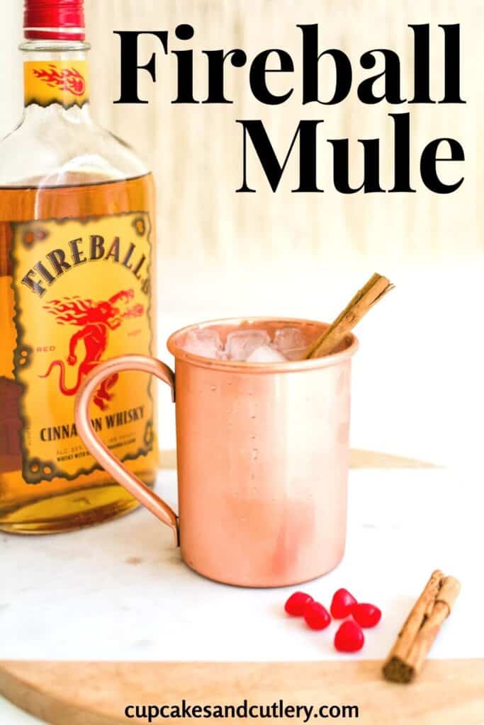 Close up of a copper mug holding a Moscow Mule and a bottle of Fireball Cinnamon Whiskey.